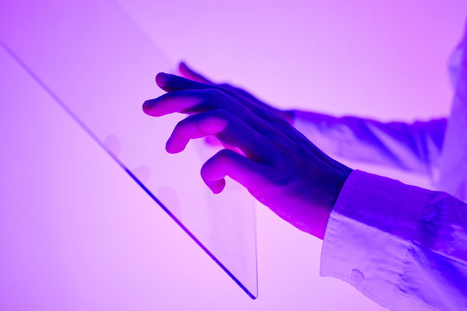 Close-up of hands interacting with a transparent glass interface in purple light